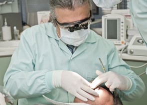 Foto de um dentista fazendo um procedimento na boca de um paciente.