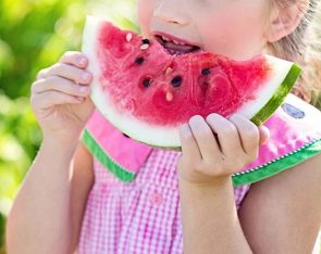 Menina comendo um pedaço de melancia